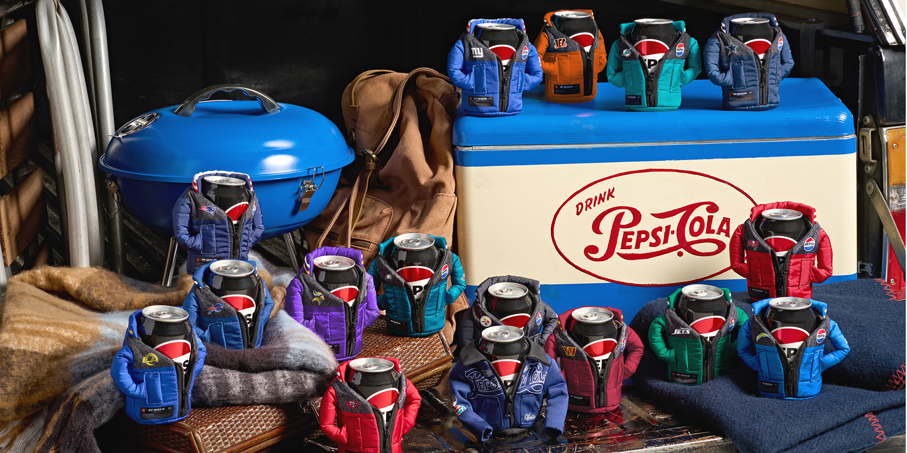 Pepsi cans wearing miniature OFF SEASON jackets in different NFL team colours at a tailgate